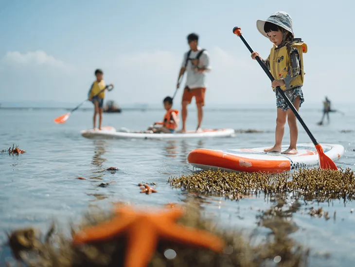 Toddler-friendly beach in Bali 2026 – Preschool-aged children participating in a guided paddle-board session in the calm, shallow lagoon.