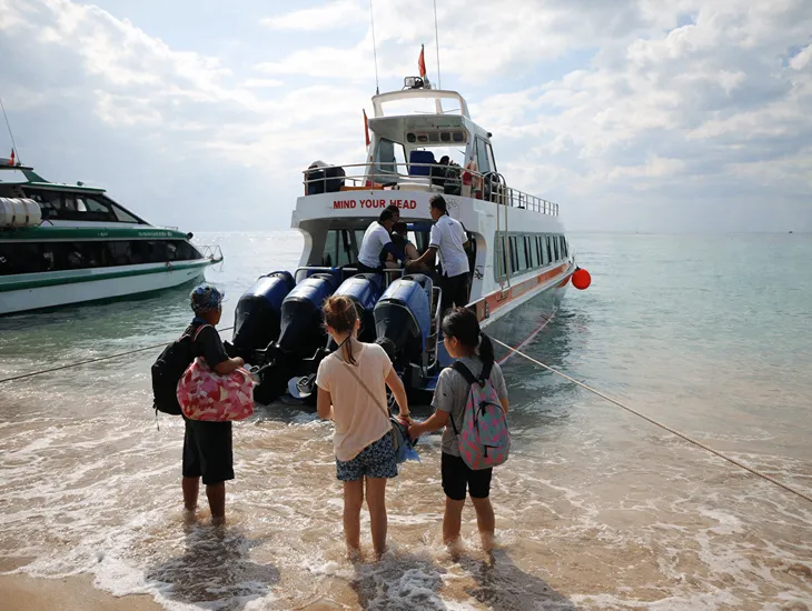 Family boarding a fast boat from Sanur to Nusa Lembongan, preparing for a Dream Beach family trip with life jackets and travel bags.