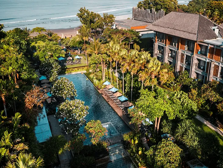 Boutique Hotels 2026 – A professional caregiver walking with a child along a paved resort pathway near the beach