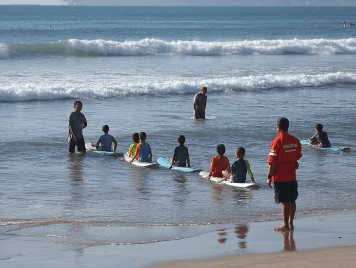 Family Hotels in Keramas, Bali 2026 – A professional lifeguard in a yellow uniform watching over a black-sand beach with a red and yellow safety flag.