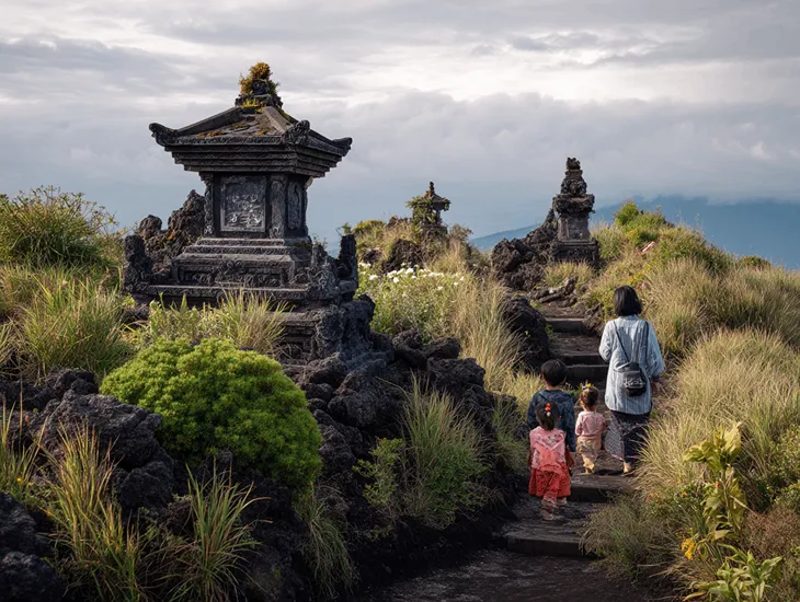 Child safety in Indonesia 2026 – A professional babysitter guiding a child carefully over loose rocks.