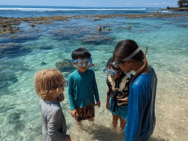 Marine Life Education 2026 – Children using snorkeling masks to observe coral reefs in a shallow Indonesian bay