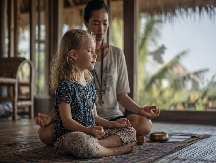 Yoga for Children 2026 – A professional childcare assistant guiding a child through a gentle stretching routine.