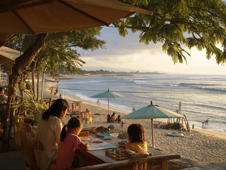 Childcare in Bali 2026 – Family walking on the sandy beach with a certified professional caregiver