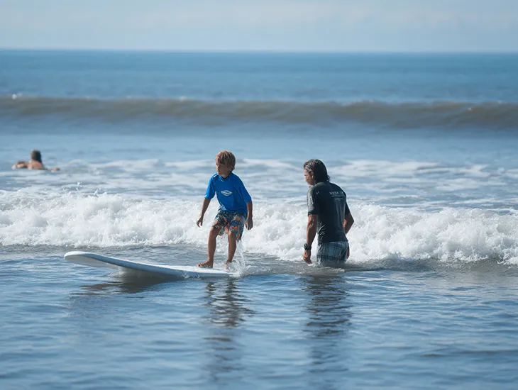 Surfing Safety in Indonesia 2026 – A certified instructor teaching a young child how to balance on a soft foam surfboard.