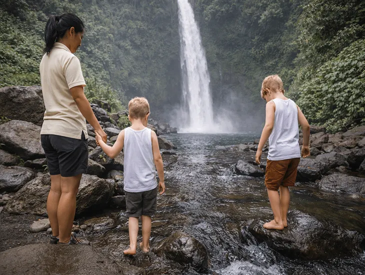 Nungnung Waterfall in Bali 2026 – A caregiver pointing out a tropical plant to a child during a rest break on the stairs.