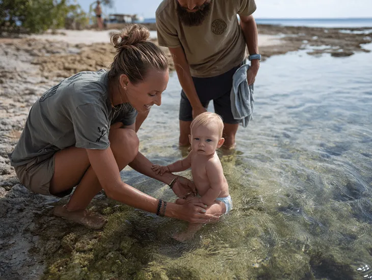 Nusa Dua Beach 2026 – Professional babysitter supervising an infant during calm water introduction in southern Indonesia